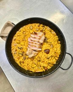 Paellera con arroz de secreto ibérico laminado a la parrilla y setas boletus recién hecha en cocina de restaurante Zeppelin Torrelodones