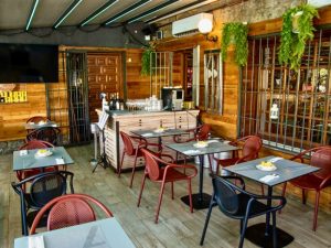 Vista general de la terraza climatizada de Restaurante Zeppelin Torrelodones con televisión para ver fútbol y mesas preparadas
