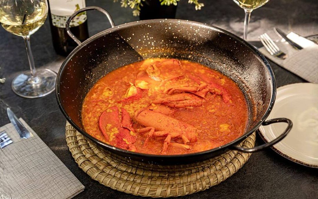 Paellera de arroz con bogavante y copas de vino blanco en mesa de Zeppelin Torrelodones para cena de Nochevieja