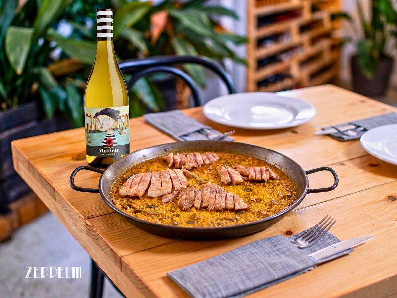 Copa de vino blanco frío Marieta junto a un plato de arroz con secreto y setas de Restaurante Zeppelin