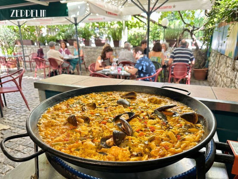 Paella y arroz seco recién servido en la terraza de Zeppelin durante una velada de verano en la sierra de Madrid