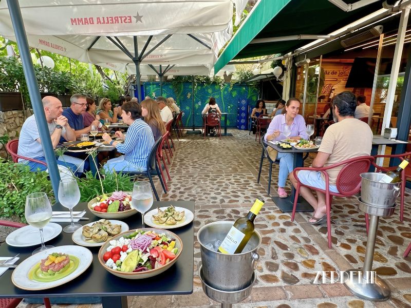 Mesa en la terraza de Zeppelin con raciones ligeras, ensaladas frescas y vino blanco helado para combatir el calor