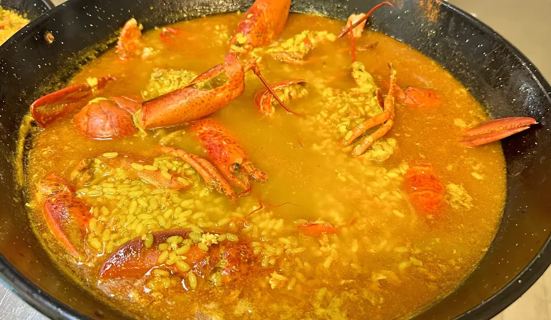Arroz caldoso con bogavante en paellera, un ejemplo claro de la diferencia entre arroz meloso y caldoso