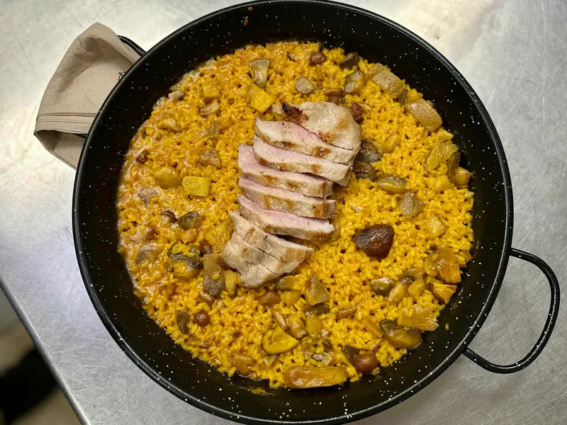 Paellera de arroz con secreto ibérico en lonchas y setas, de grano suelto y color dorado